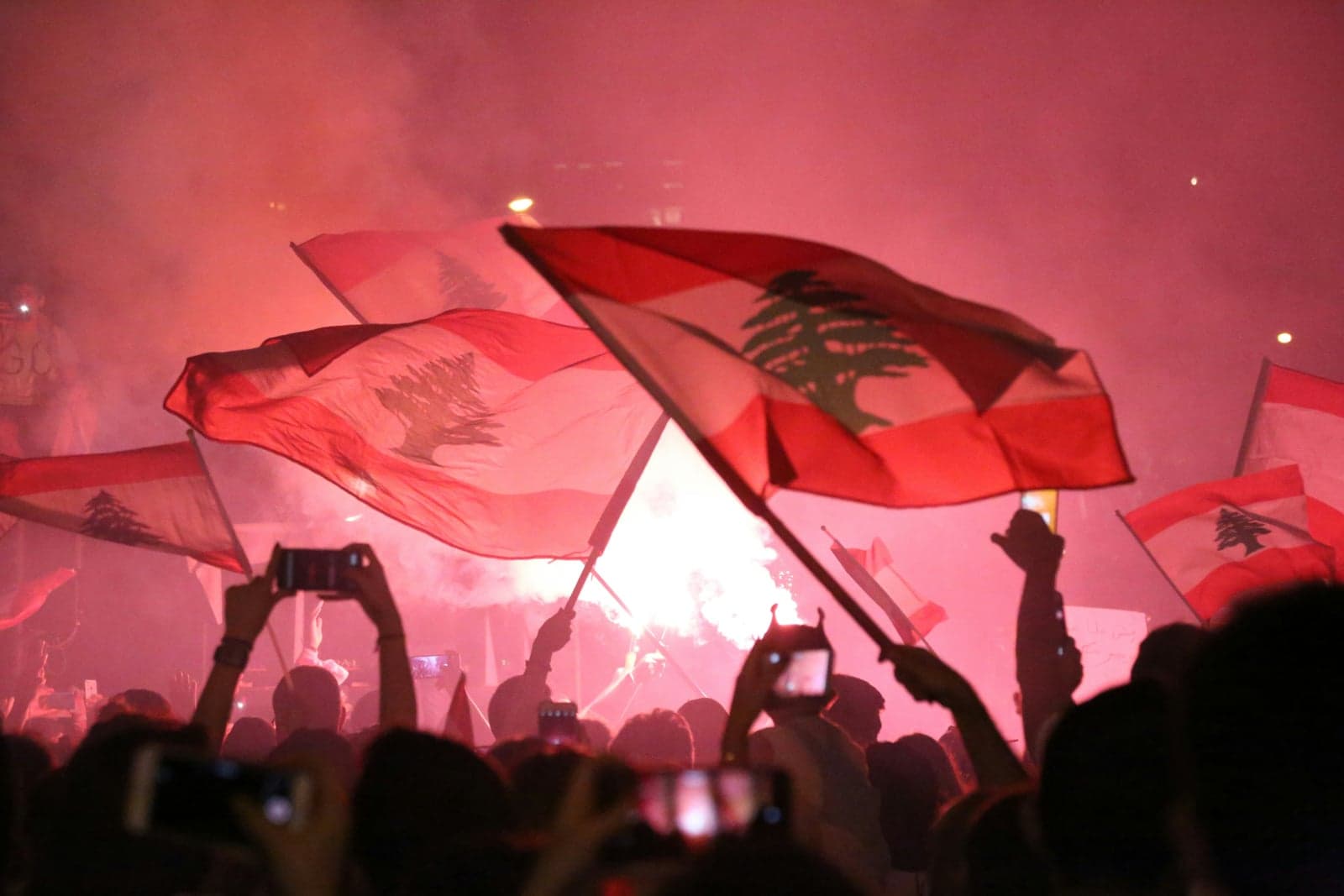 Picture of people demonstrating while waving Lebanese flags in the air